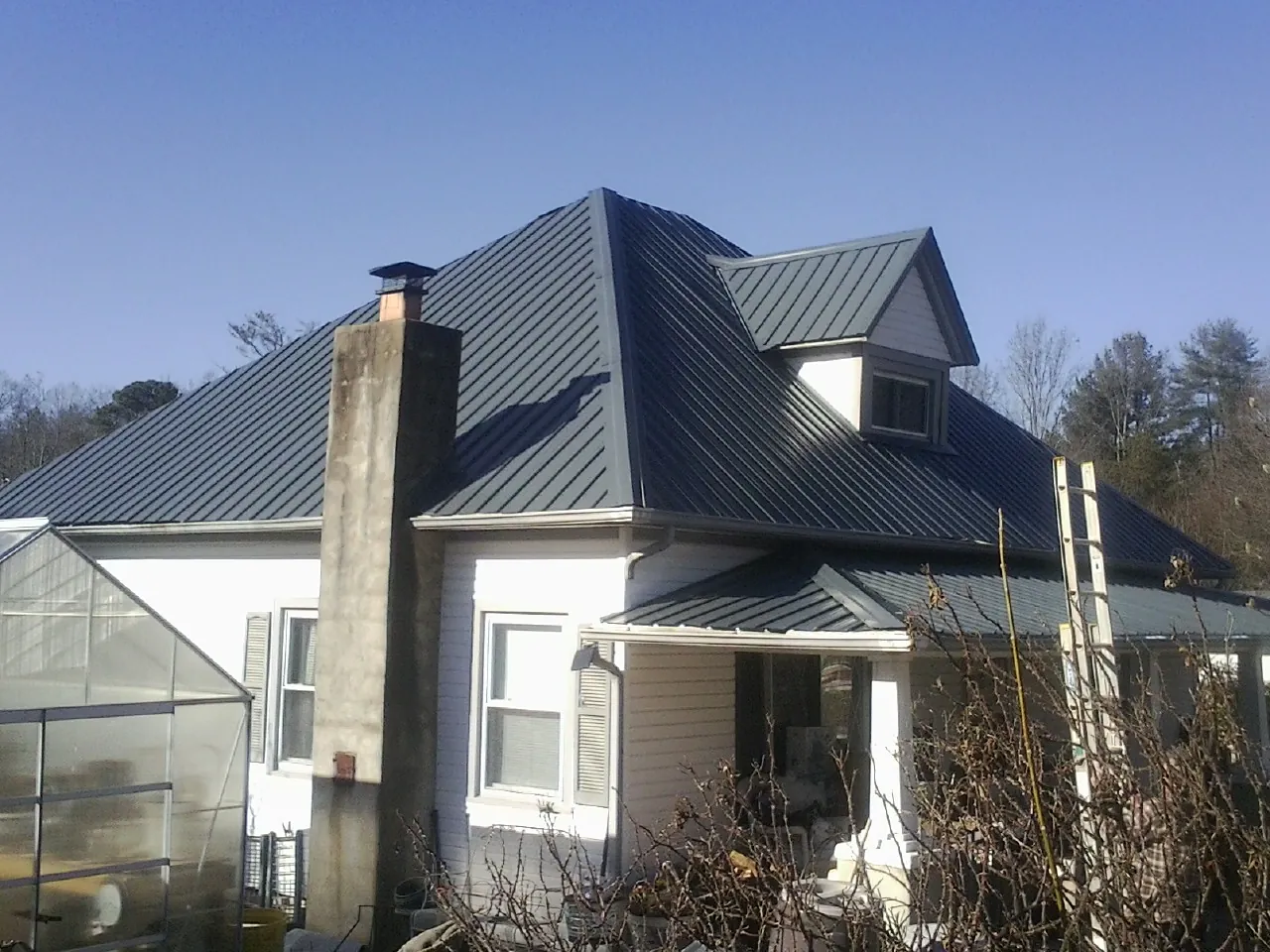 Dark blue standing seam metal roof on a white farmhouse with dormer — Slate & Tile Roof Repair by Roofing Brothers in Parsonsburg