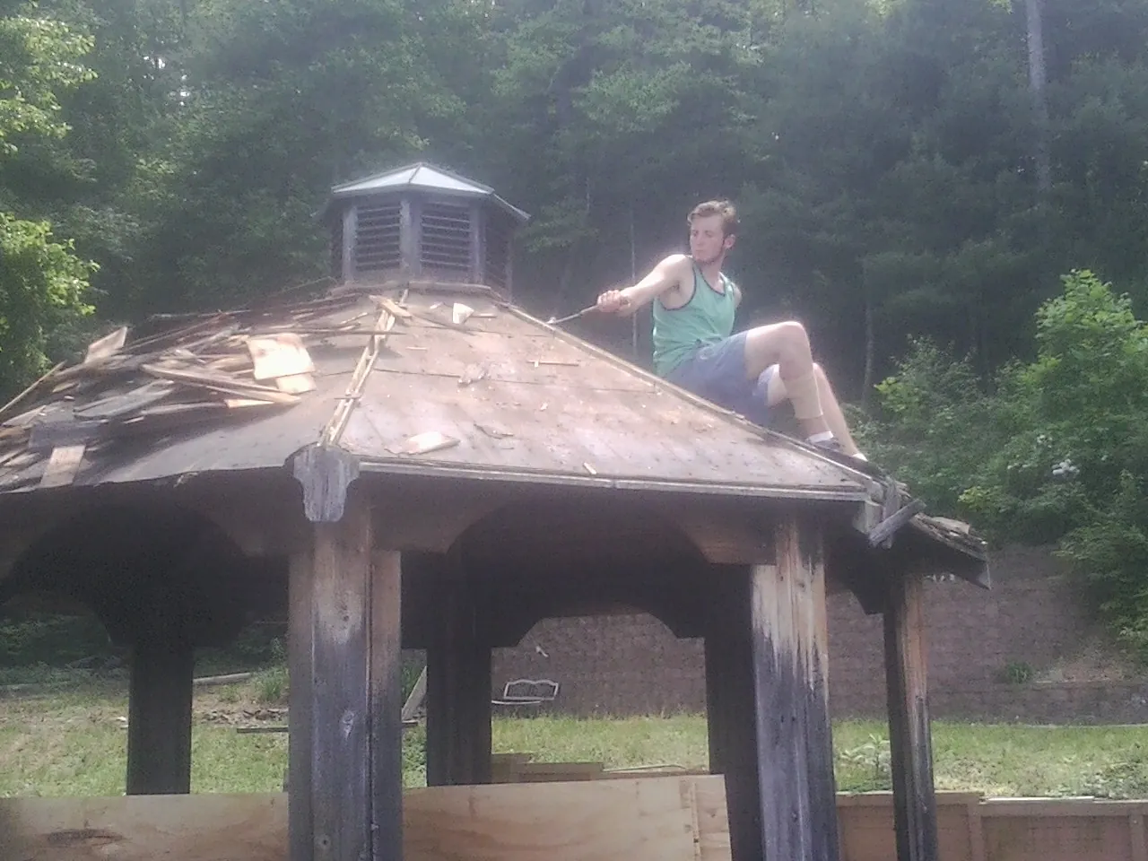 Tearing the old roof off a wooden gazebo before new shakes in Parsonsburg