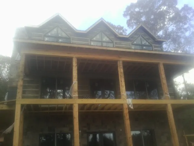 Dormers and porch framing on a large log home under construction — Roof Coating work by our crew in Parsonsburg