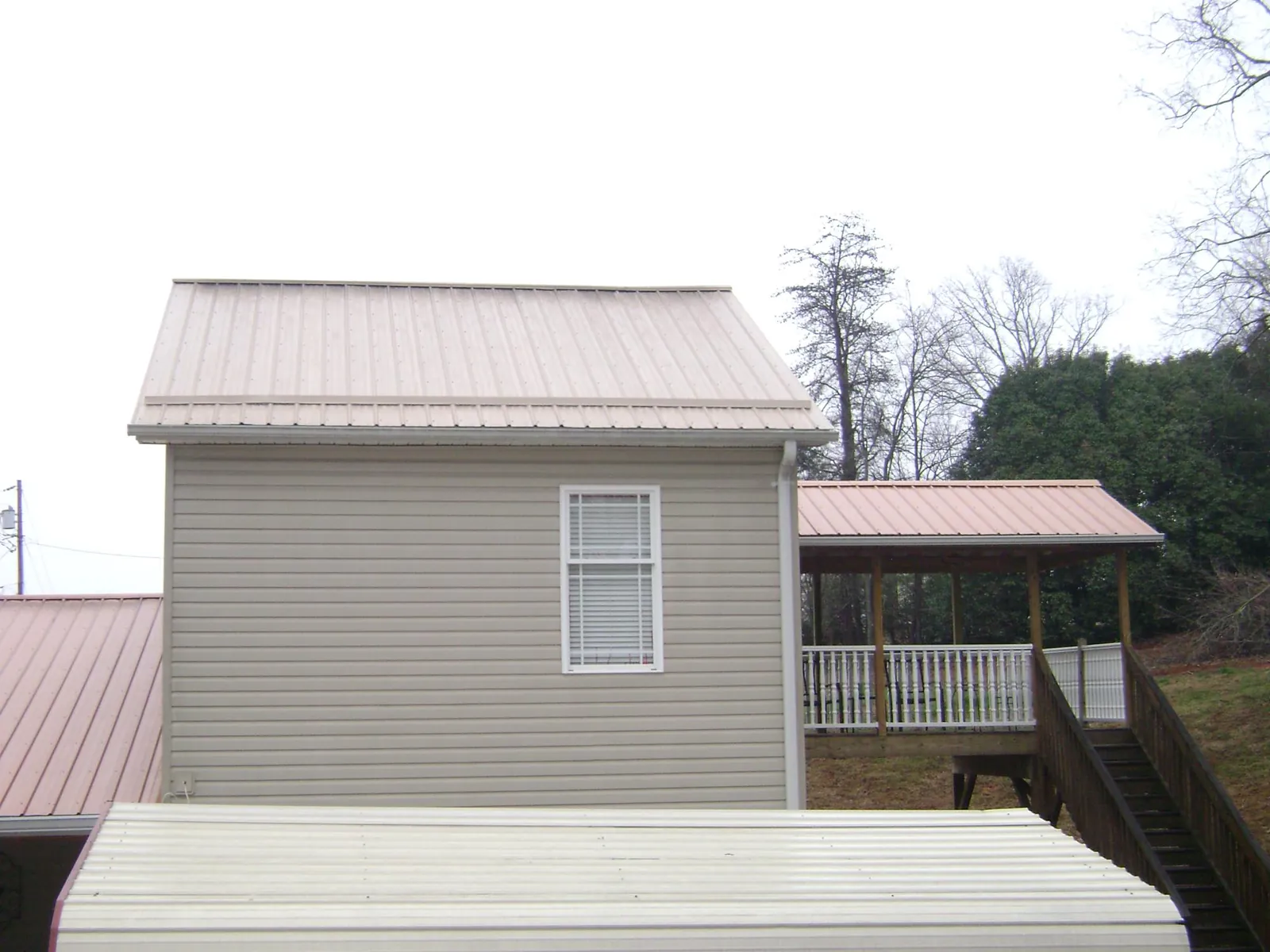 Tan metal roofs on a two story addition and attached porch, from a Roof Replacement job in Parsonsburg